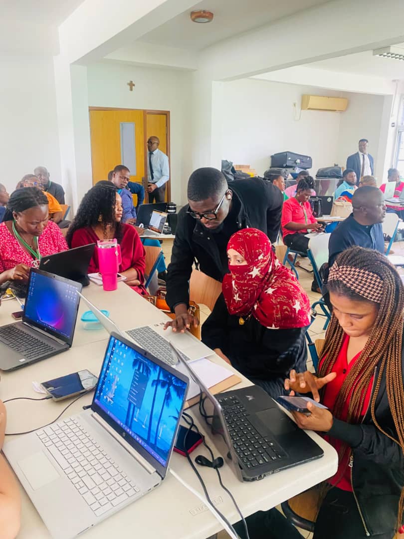 Trainer supporting participants at laptops during training